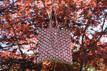 Load image into Gallery viewer, pink arthus block print bag hanging in an acer tree
