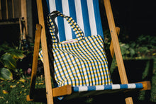 Load image into Gallery viewer, bertie block print bag with blue and yellow gingham on a blue striped deckchair
